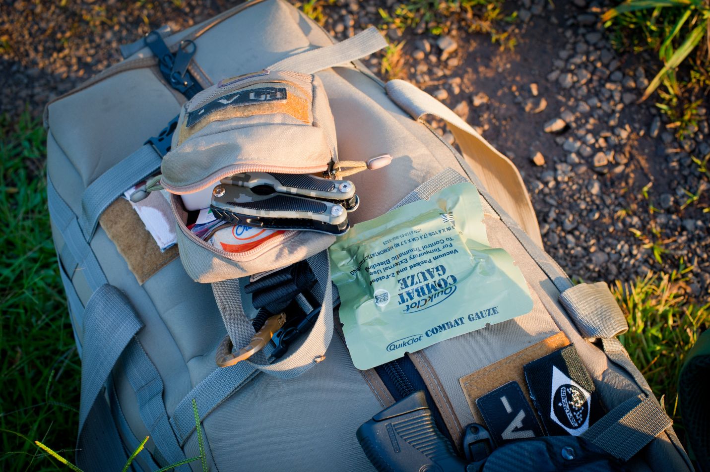 Khaki duffle bag with survival equipment sitting on the ground outside