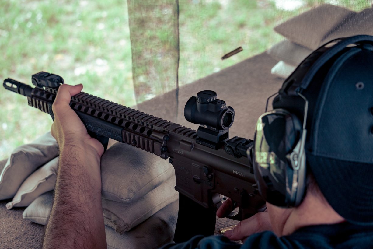 A man looking through the sight of a black AR-15