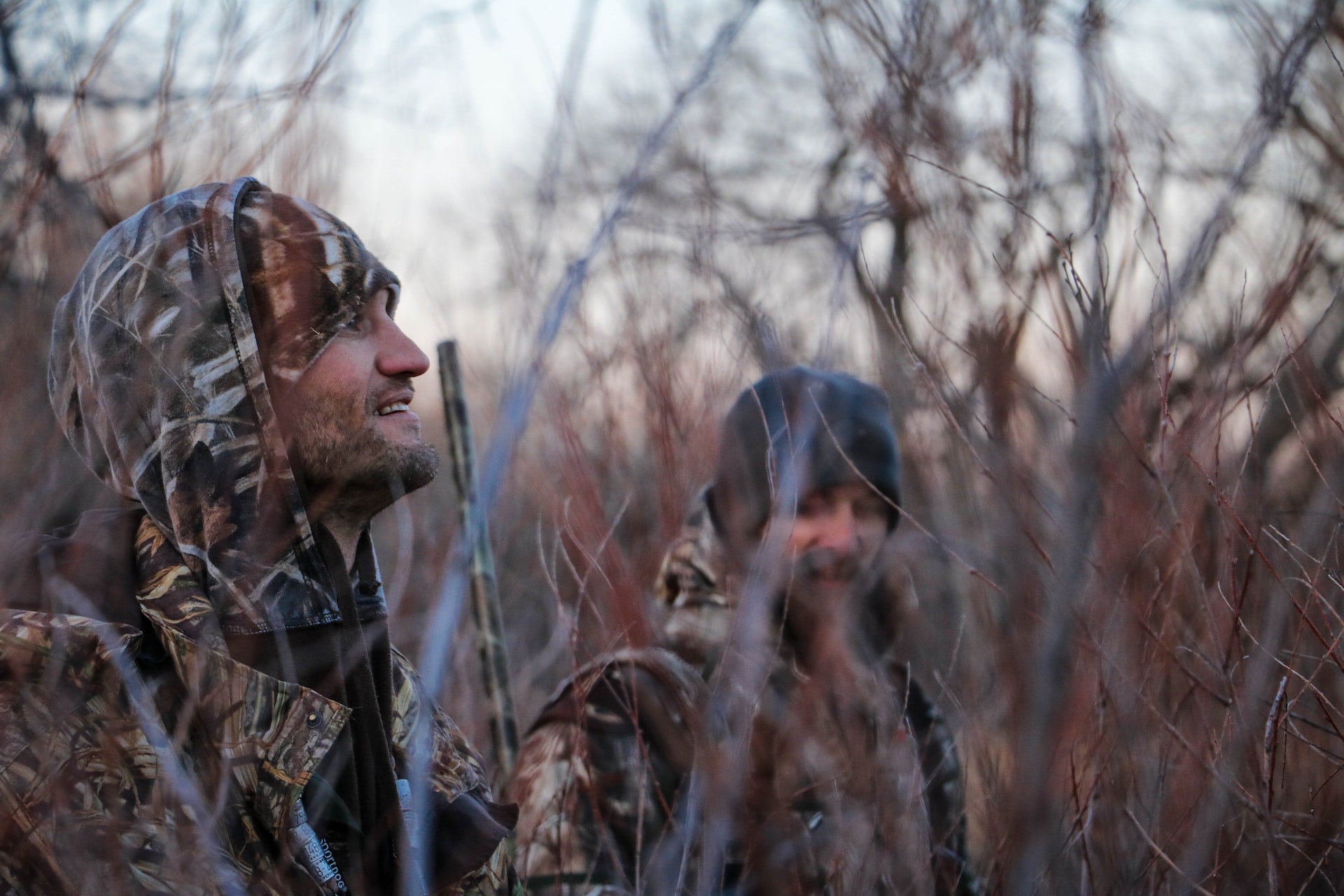 Two men in camo hiding in the forest
