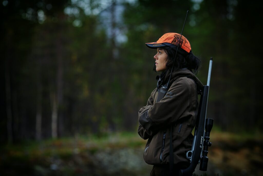 Woman carrying a hunting rifle in the woods
